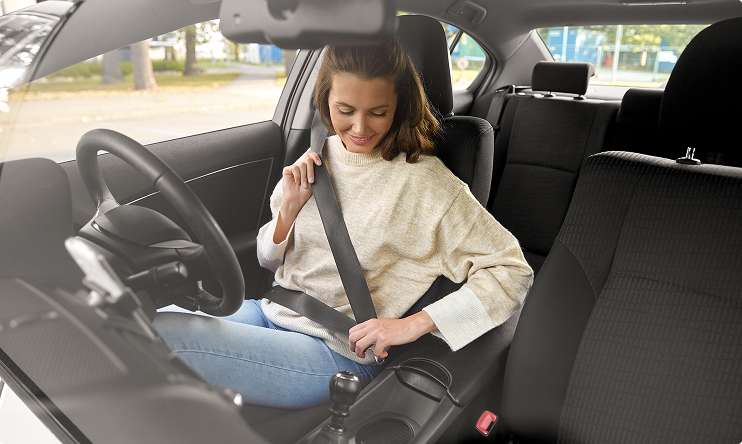 Lady in a car fastening her seatbelt